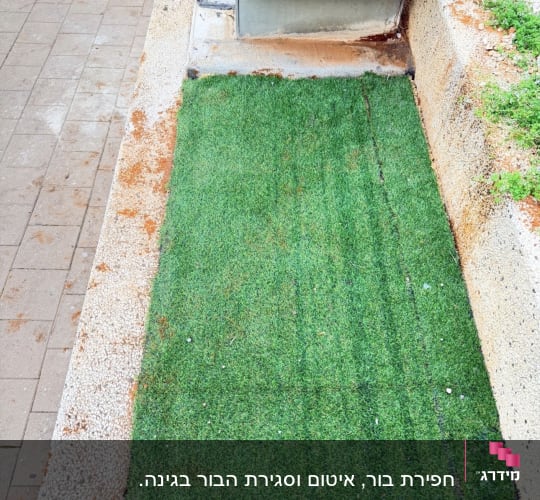 שטח דשא מלאכותי ליד מבנה בטון קטן